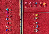 Bogura, Bangladesh - 28 January 2021: Aerial view of vibrant red chili peppers drying under the sun, contrasting with the people working on the field.