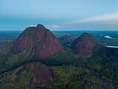 Aerial view of dramatic tepuis rise majestically from the emerald jungle, their weathered faces kissed by the soft glow of twilight, Puerto Inírida, Cerros Mavicure, Colombia.