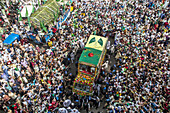 Chattogram, Bangladesh - 08 October 2022: Aerial view of a vibrant procession of people, surrounding a decorated vehicle with flags, creating a sea of white garments under the bright sky.