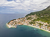 Luftaufnahme der Küstenstadt Igrane in der Gespanschaft Split-Dalmatien, Kroatien, eingebettet zwischen der türkisfarbenen Adria und den üppig grünen Bergen.