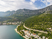 Luftaufnahme der Küstenstadt, eingebettet zwischen der türkisfarbenen Adria und den hoch aufragenden, zerklüfteten Bergen, eine Symphonie aus Blau-, Grün- und Grautönen, Drvenik, Gespanschaft Split-Dalmatien, Kroatien.