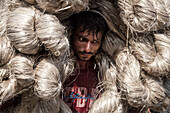 Jamalpur, Bangladesh - 18 August 2023: View of a man amidst a mountain of jute, his face etched with sweat and determination, a testament to labor in the heart of the jute trade.