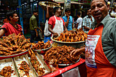 Bogura, Bangladesh - 15 June 2017: View of a vibrant street food vendor, his face alight with pride amidst the golden-brown hues of freshly fried snacks.