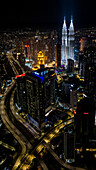 Aerial view of Petronas Twin Towers and city lights illuminate the night, casting a golden glow over Kuala Lumpur's skyline, Kuala Lumpur, Federal Territory of Kuala Lumpur, Malaysia.