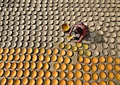 Bogura, Bangladesh - 22 October 2019: Aerial view of a craftsman meticulously painting clay pots, the ochre hues contrasting against the sun-baked earth and unpainted pottery.