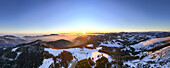 Aerial view of sun-kissed snow blankets the rolling hills, casting long shadows over the Almenland's winter wonderland landscape, Sommeralm, Steiermark, Austria.