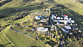 Aerial view of a village nestled amid rolling green hills, touched by early winter's frost, Posof, Ardahan, Türkiye.