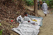 Chandanath hill, Bangladesh - 12 March 2021: View of a man resting on a makeshift bed near the footpath, under the shade of trees, with fallen leaves scattered around.