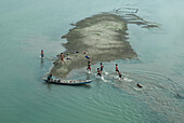 Rangpur, Bangladesch - 30. November 2019: Luftaufnahme einer kleinen Insel im Fluss, auf der Kinder spielen und schwimmen, ein Boot, das in der Nähe des Ufers liegt, alles unter einem ruhigen, bedeckten Himmel.