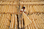 Bogura, Bangladesh - 04 May 2023: Aerial view of a young boy amidst the golden threads of sun-dried noodles, creating a textured tapestry under the open sky.