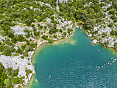 Luftaufnahme des türkisfarbenen Wassers, das auf felsige Küsten und üppiges Grün trifft, eine ruhige Szene, die von oben aufgenommen wurde, Sibenik, Gespanschaft Sibenik-Knin, Kroatien.