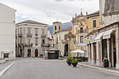 Blick auf sonnendurchflutete Gebäude mit verzierten Fassaden und einer Bergkulisse, die ein zeitloses Tableau im Herzen der Stadt bilden, Sulmona, Abruzzen, Italien.