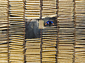 Bogura, Bangladesh - 05 September 2020: Aerial view of rows of sun-dried food create a geometric pattern, with a worker in blue adding a human touch to the scene.