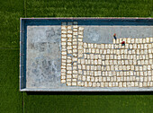 Bogura, Bangladesh - 30 July 2025: Aerial view of a vast concrete platform speckled with drying food, contrasting against the vibrant green paddy fields.