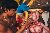 Bogura, Bangladesh - 16 October 2020: View of an artist meticulously painting the eyes of a Durga idol, the vibrant colors bringing life to the clay figure.