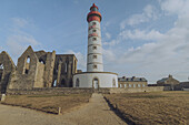 View of the towering Phare de Saint-Mathieu lighthouse stands boldly against the ruins, a beacon of hope amidst a landscape frozen in time, Plougonvelin, Bretagne, France.