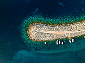 Aerial view of a stone pier embracing the turquoise sea, small boats bobbing gently in the crystal-clear water, a tranquil scene of coastal beauty, Malta.