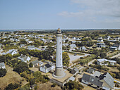 Aerial view of the stark white Phare de Trezien lighthouse piercing the skyline amidst a sea of quaint houses and verdant foliage, Plouarzel, Bretagne, France.