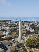 Aerial view of the tall, white Phare de Trezien lighthouse standing majestically against the backdrop of the shimmering blue sea, Plouarzel, Bretagne, France.