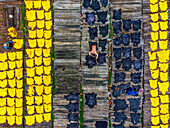 Dhaka, Bangladesh - 20 August 2023: Aerial view of vibrant yellow and stark black hides drying in neat rows, contrasting against the muted tones of the tannery workers and weathered surfaces.