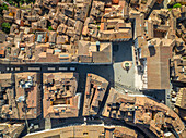 Luftaufnahme von sonnenüberfluteten Dächern und alten Straßen, die auf einer zentralen Piazza mit einem Brunnen zusammenlaufen und lange Schatten im Herzen der Stadt werfen, Perugia, Umbrien, Italien.