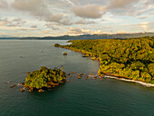 Aerial view of a rugged coastline where the dense, verdant jungle meets the tranquil turquoise ocean, Nuquí, Choco, Colombia.