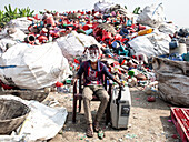 Sirajganj, Bangladesh - 10 January 2025: View of a young boy amidst a mountain of discarded plastic, a stark contrast against the muted sky.