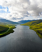 Aerial view of serene waters reflecting the sky between grassy hills near Haldarsvík and Langasandur, Streymoy, Faroe Islands.