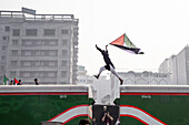 Tongi, Bangladesh - 03 February 2024: View of a vibrant leap over green trains, flag waving high against the urban backdrop.