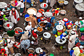 Tongi, Bangladesh - 31 January 2025: Aerial view of a bustling open-air food preparation area, vibrant with colorful ingredients and busy cooks amidst a sea of gleaming metal pots and containers.
