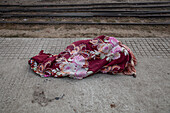 Tongi, Bangladesh - 02 February 2025: View of a discarded maroon and pink floral blanket on the cold, grey platform near the train tracks.