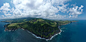Aerial view of rugged cliffs meet the vast, deep blue ocean under a sky dotted with fluffy clouds, Azores, Portugal.