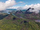 Aerial view of Mavicure Hills, dark rivers snaking between, shrouded in mist and clouds, a symphony of green jungle and stark rock, Puerto Inírida, Cerros Mavicure, Colombia.