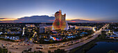 Hollywood, Florida, United States - 14 August 2025: Aerial view of the vibrant, guitar-shaped Hard Rock Hotel, pulsating with light against the twilight sky, amidst lush greenery and flowing traffic.