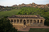 Aerial view of the ancient arched structure stands in striking contrast against the lush green landscape and rocky hills, Hampi, Karnataka, India.