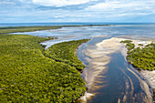Luftaufnahme des sich schlängelnden Flusses, der auf den weiten Ozean trifft, mit üppiger grüner Vegetation im Kontrast zum blauen Wasser, Diani Beach, Kwale County, Kenia.