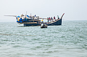 Cox's Bazar, Bangladesh - 07 February 2024: View of a traditional fishing boat laden with nets and fishermen along Cox's Bazar - Teknaf Highway, against a hazy horizon.