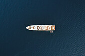 Aerial view of a luxury yacht cutting through the deep blue sea, a study in contrasts of pristine white against the infinite azure, Sicily, Italy.