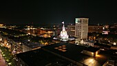 Aerial view of the gold-domed City Hall illuminated against the night sky, contrasting with the dark rooftops and twinkling city lights, Savannah, Georgia, United States.