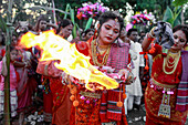 Sylhet, Bangladesh - 08 November 2022: View of a vibrant ceremony unfolds, with women in traditional attire holding flames against a backdrop of lush greenery and onlookers.