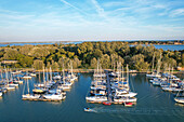 Aerial view of yachts moored on the shimmering turquoise waters of the marina, reflecting the azure sky above, Venice, Veneto, Italy.