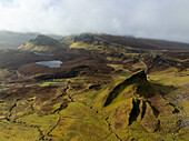 Aerial view of the Quiraing's dramatic rock formations under a blanket of low-hanging mist, revealing a landscape of rugged beauty and serene isolation, Isle of Skye, Scotland, United Kingdom.