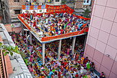 Dhaka, Bangladesh - 12 November 2022: Aerial view of a vibrant, bustling gathering of people in colorful attire, sharing a meal on an elevated platform, contrasting against the surrounding buildings.