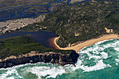 Luftaufnahme der Mündung des Gellibrand River in den Ozean, ein starker Kontrast zwischen dem dunklen Flusswasser und den schäumenden weißen Wellen, die auf den goldenen Strand prallen, Princetown, Victoria, Australien.