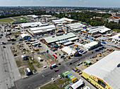 Munich, Germany - 18 August 2025: Aerial view of the bustling Theresienwiese fairgrounds, a vibrant tapestry of structures, vehicles, and activity under a clear, expansive sky.