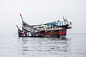 Cox's Bazar, Bangladesh - 01 January 2000: View of the traditional fishing boats with red and black hulls, gently rocking on the tranquil, silver-toned waters of the Bay of Bengal.