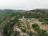 Aerial view of the ancient Tatev Monastery clinging to the edge of a precipitous cliff, its stone walls a testament to time and faith, Tatev, Syunik Province, Armenia.