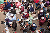 Tongi, Bangladesh - 02 February 2025: Aerial view of devotees in vibrant clothing and white caps, heads bowed in prayer on a street, contrasting with the gray pavement.