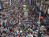 Chattogram, Bangladesh - 16 September 2024: Aerial view of a bustling street filled with a dense crowd, vibrant green flags, and ornately decorated vehicles.