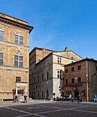 Tuscany, Italy - 23 April 2025: View of the town square, Pienza, where warm stone buildings meet clear blue skies, creating a timeless Italian scene.